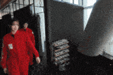 a woman in a red jumpsuit has a sticker on her shoulder that says ' a ' on it