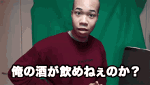 a man wearing a maroon playboy sweater stands in front of a green background