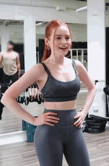 a woman in a sports bra and leggings stands in front of a mirror with her hands on her hips