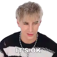 a man with blonde hair is wearing a black and white striped sweater and a necklace and says it 's ok