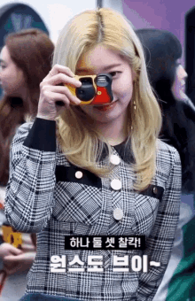 a woman in a plaid shirt is holding a yellow camera