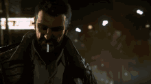 a man with a beard is smoking a cigarette in a dark city
