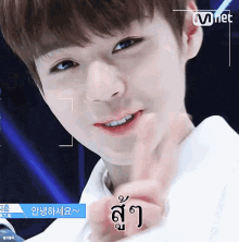 a close up of a young man 's face with a finger on his lips and the word mnet on the bottom right corner .