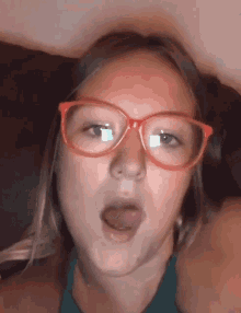 a young girl wearing red glasses is making a face