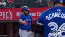 a baseball player wearing a blue jays jersey stands in front of a pep 's ad