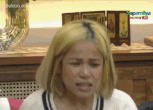 a woman is making a face in front of a sign that says kapamlive