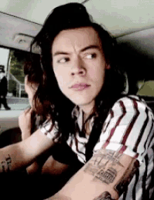 a man with long hair is sitting in a car and looking at the camera .