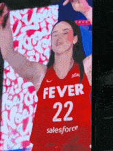 a woman in a red fever 22 jersey is standing in front of a screen .