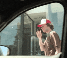 a man wearing a red and white hat is standing in front of a building that says ' a ' on it