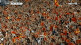 a crowd of people are watching a soccer game on a television screen