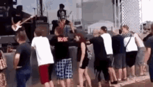 a group of people are standing in front of a stage at a music festival .