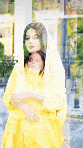 a woman in a yellow dress is holding a child
