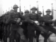 a black and white photo of a group of soldiers marching in a line .