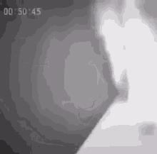 a black and white photo of a person 's face with the time of 00 50 45