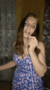a woman in a blue dress is singing into a microphone while wearing headphones .