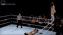 two women are wrestling in a wrestling ring with a referee standing in the middle .