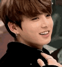 a close up of a person wearing earrings and a ring smiling .