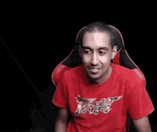 a man in a red t-shirt is sitting in a black chair