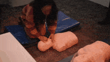 a woman is practicing on a mannequin with her hands on it 's chest
