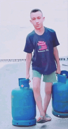 a young man wearing a shirt that says washington dc is carrying two blue gas cylinders