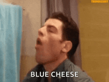 a man is eating blue cheese in a bathroom while looking at himself in the mirror .