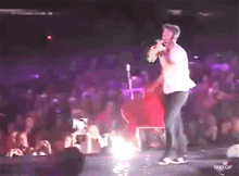a man is singing into a microphone on a stage in front of a crowd