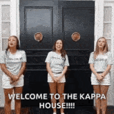 three women are standing in front of a black door with the words welcome to the kappa house .