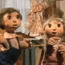 two stuffed dolls are standing next to each other in a room .
