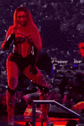a woman is singing into a microphone on a stage in front of a crowd of people .