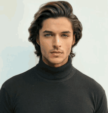 a man wearing a black turtleneck sweater looks at the camera