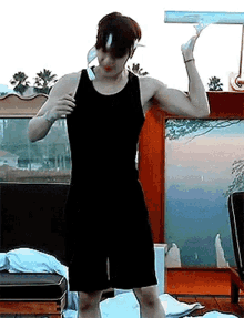 a man in a black tank top and black shorts is flexing his muscles in a room .