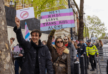 a man holding a sign that says " hey nhs leave trans kids alone "