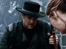 a man in a cowboy hat is holding a gun and talking to a woman