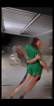 a woman in a green shirt is being lifted by a man