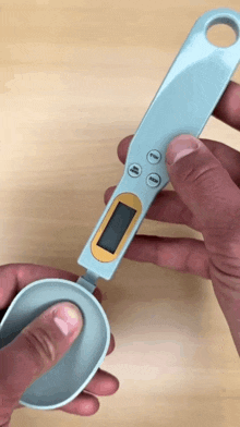 a person is holding a digital measuring spoon with a display that says grams