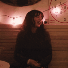 a woman laughs in front of a hawaiian ring toss sign