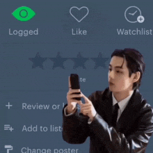 a man in a suit is holding a cell phone in front of a screen that says liked and watchlist