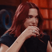 a woman with red hair and a tattoo on her wrist