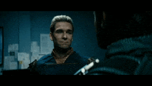 a man in a superhero costume looks at another man in a dark room with papers on the wall