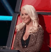 a woman is sitting in a red chair with her arms crossed .