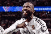 a soccer player wearing a white emirates jersey is pointing at the camera
