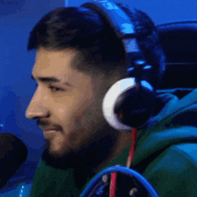 a man wearing headphones and a green sweatshirt is smiling