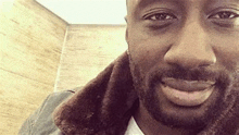 a close up of a man with a beard wearing a fur coat .