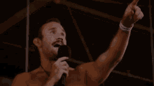 a man without a shirt is holding a microphone and pointing