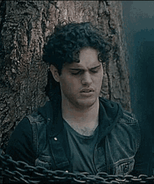 a young man is chained to a tree with a chain .