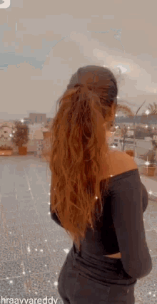 a woman with long brown hair is wearing a black off the shoulder top .