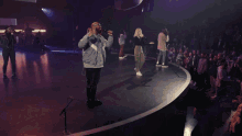 a man is singing into a microphone while another man stands behind him .
