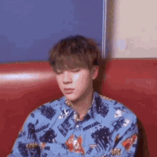 a young man in a blue shirt is sitting on a red chair .
