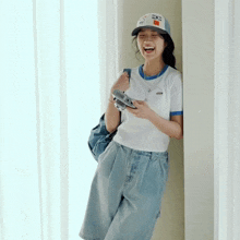 a woman wearing a hat that says kodak on it holds a camera
