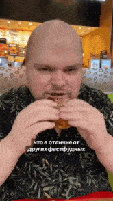a bald man is eating a hamburger in a fast food restaurant in a foreign language ..